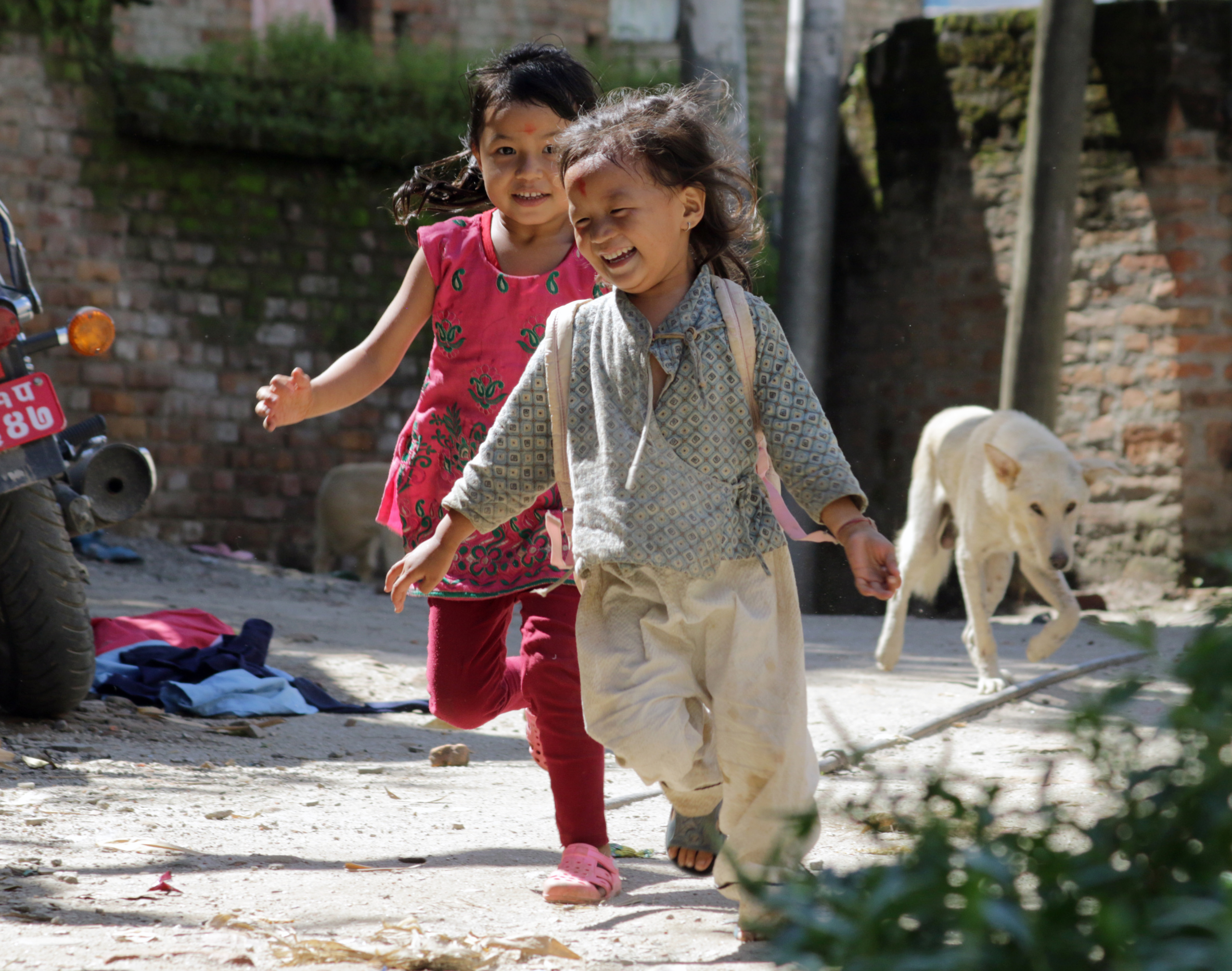 kaksi iloista lasta juoksee Nepalissa. Tue Nepalin tyttöjen oikeuksia!