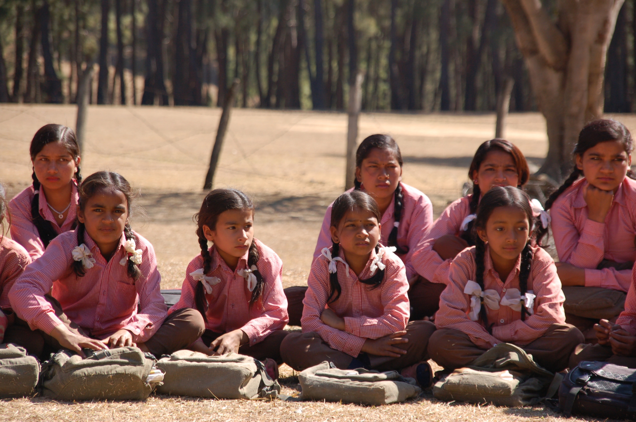 Nepalilaisia tyttöjä koulupuvuissa istuu maassa