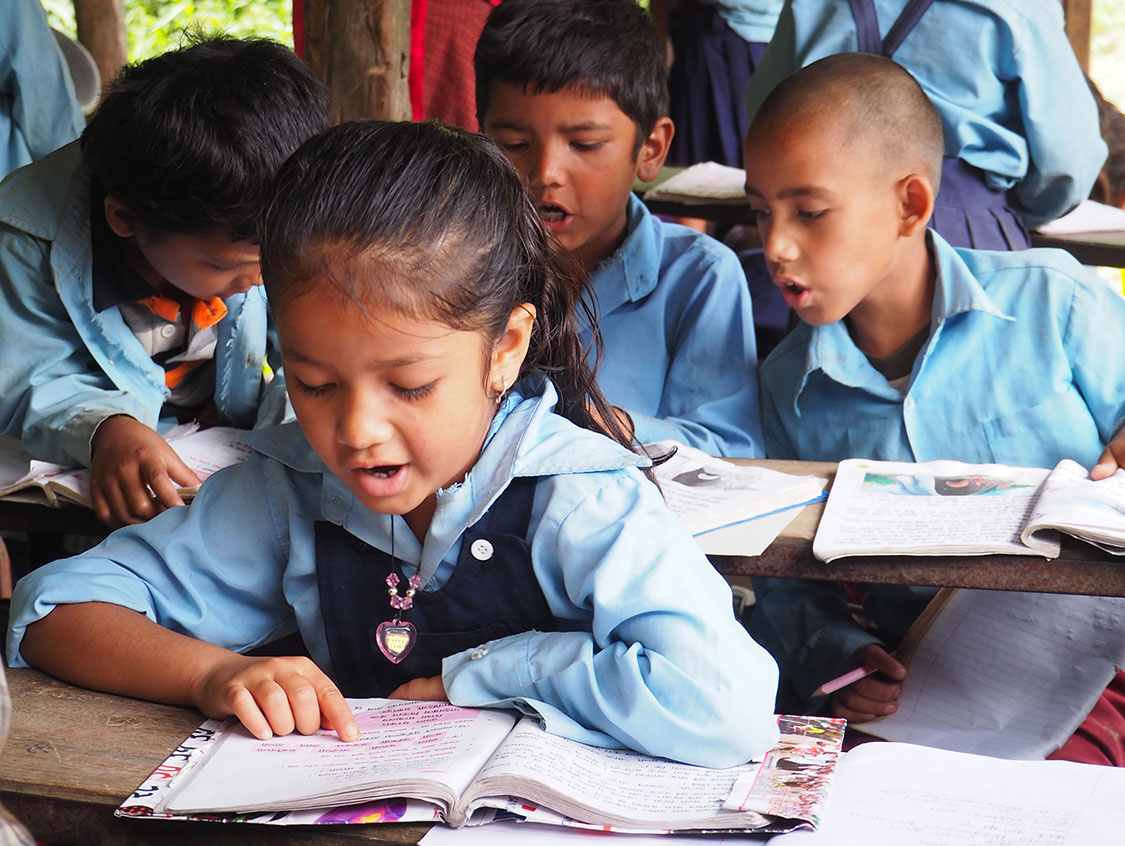 Nepalailaislapset lukevat ääneen koulussa. Kummiohjelmat tukevat koulunkäyntiä.