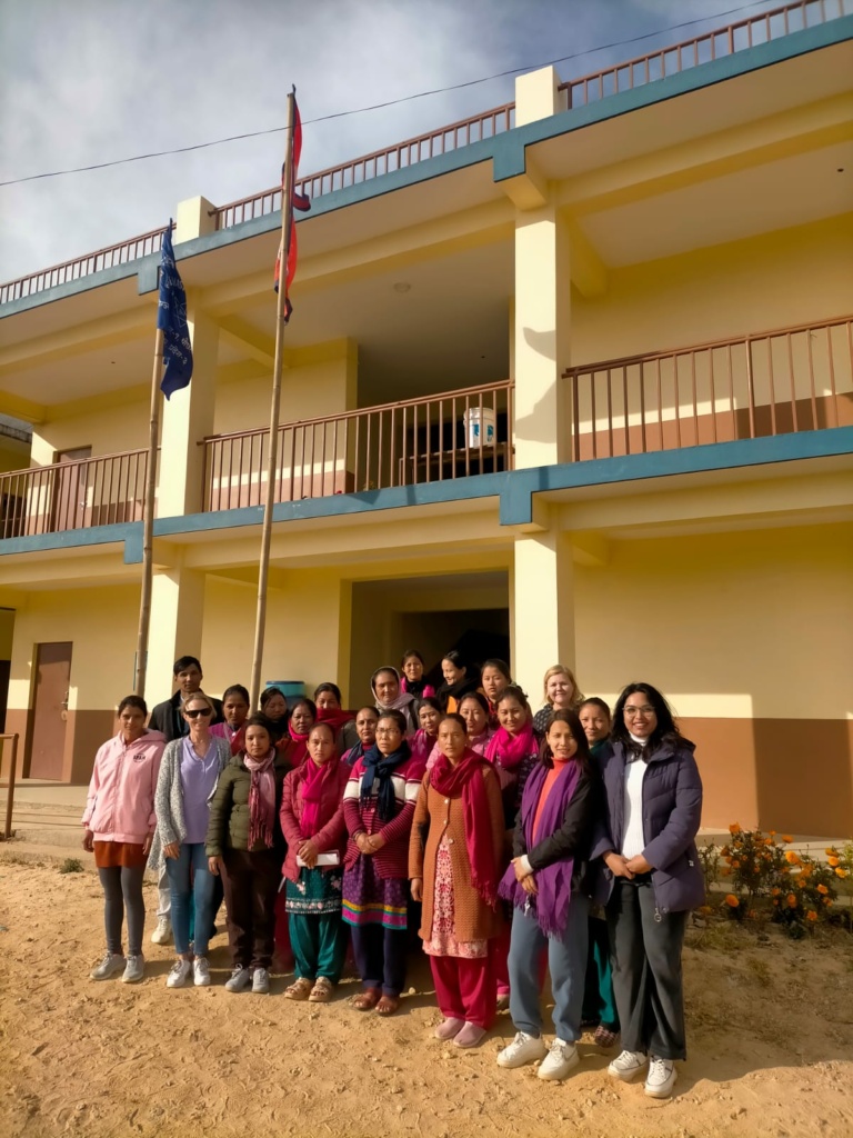 Ryhmä nepalilaisia ja suomalainen vapaaehtoinen toimistorakennuksen edessä